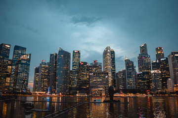 Evening photo of illuminated Singapore business quarter reflected in the water of the Bay during dusk