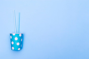Blue paper cup in dot for cocktails with a straw isolated on background. Copy space