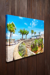 Canvas photo print on brown wooden background. Sample of gallery wrapping method of canvas stretching on stretcher bar. Side view of colorful photography hanging on wall