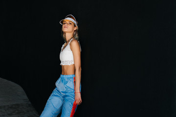 sporty beauty in a visor proudly stands in studio background black