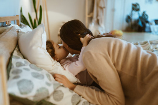 daughter kisses mom at night before bed
