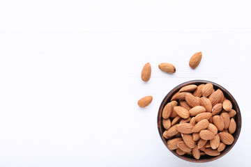 Almonds in bowl on white wooden table