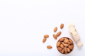 Almonds in bowl and scoop on white wooden table