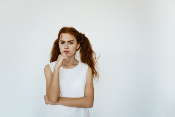 schoolgirl with a puzzled look holds his hand on her chin. bright studio