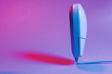 Picture of a white computer mouse standing straight up on a coloured background