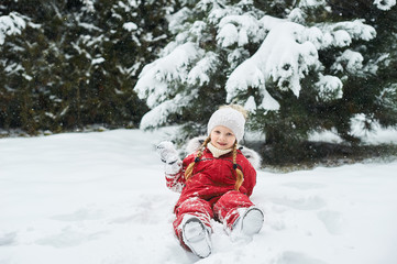 Fototapeta na wymiar portrait of a beautiful caucasian child on a background of snow-covered Christmas trees