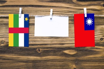 Hanging flags of Central African Republic and Taiwan attached to rope with clothes pins with copy space on white note paper on wooden background.Diplomatic relations.