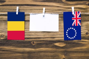 Hanging flags of Chad and Cook Islands attached to rope with clothes pins with copy space on white note paper on wooden background.Diplomatic relations between countries.