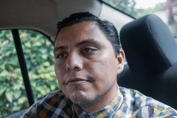 Hispanic young man in a car checking his social media in his smartphone.