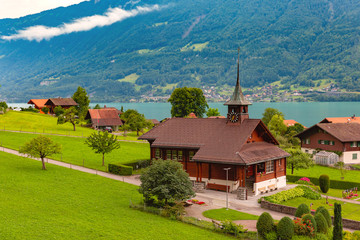 Fototapeta na wymiar Swiss village Iseltwald with traditional wood church on the southern shore of Lake Brienz, Switzerland