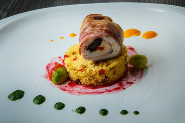 closeup choped meat roll served on quinoa with vegetables and sauces