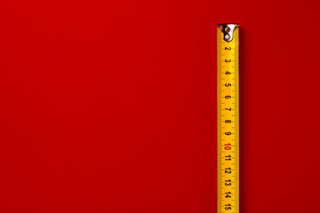 Yellow measuring tape on red background