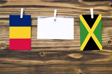Hanging flags of Chad and Jamaica attached to rope with clothes pins with copy space on white note...