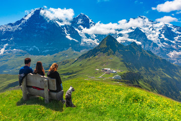 Fototapeta premium Tourists admire Eiger, Monch and Jungfrau mountains from summit of mountain Mannlichen, popular viewpoint in Swiss Alps, Switzerland.