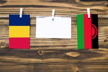 Hanging flags of Chad and Malawi attached to rope with clothes pins with copy space on white note...