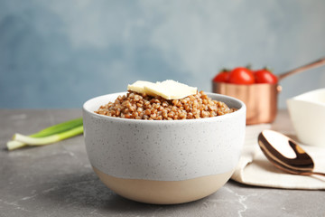 Bowl of buckwheat porridge with butter on grey marble table