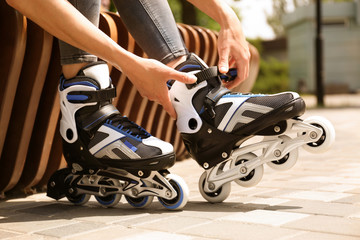 Fototapeta na wymiar Woman wearing modern inline roller skates in city park, closeup