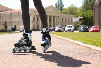 Woman with modern inline roller skates in city park, closeup