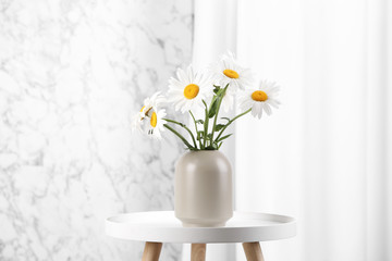 Beautiful tender chamomile flowers in vase on white table indoors