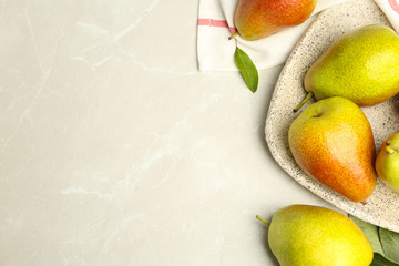 Plate with ripe juicy pears on light stone table, flat lay. Space for text