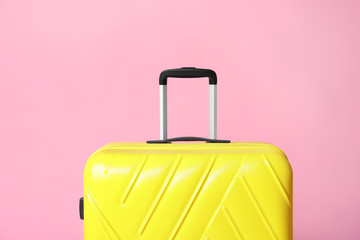 Modern yellow suitcase on light pink background
