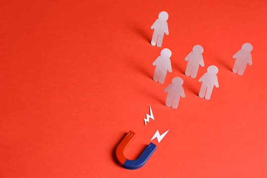 Magnet attracting paper people on red background, space for text. Business rivalry concept