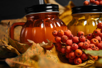     Autumn composition of glasses in the form of a pumpkin on a background of leaves and mountain ash  