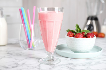 Tasty milk shake and strawberries on white marble table
