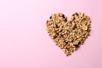 Heart made of ingredients for homemade healthy granola bars on pink background, flat lay. Space for text