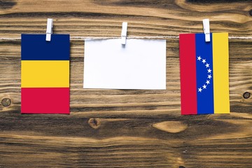 Hanging flags of Chad and Venezuela attached to rope with clothes pins with copy space on white...