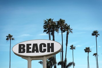 Naklejka premium aged and worn beach sign and palm trees