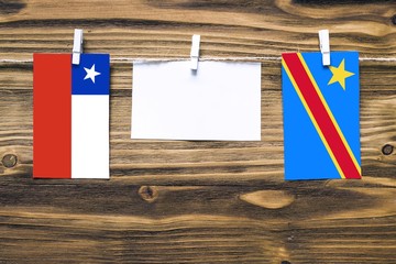 Hanging flags of Chile and Congo attached to rope with clothes pins with copy space on white note paper on wooden background.Diplomatic relations between countries.