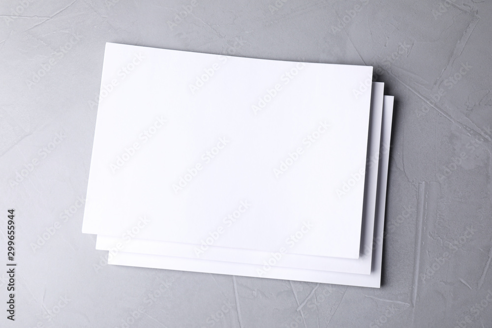 Wall mural blank paper sheets on light grey stone background, top view. mock up for design