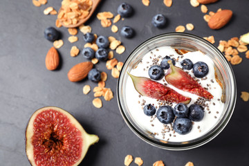 Tasty homemade granola with yogurt on dark grey table, flat lay. Healthy breakfast