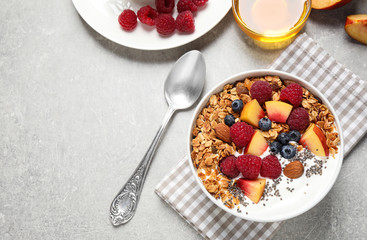 Healthy homemade granola with yogurt served on grey table, flat lay. Space for text