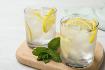 Glasses of cocktail with vodka, ice and lemon on white wooden table