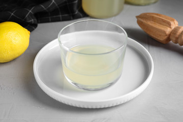 Freshly squeezed lemon juice in glass bowl on grey table