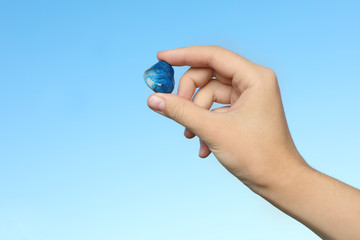 Woman holding shattuckite gemstone against blue background, closeup