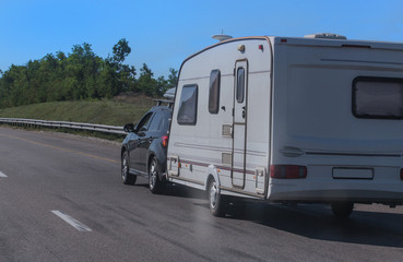 SUV with a camping trailer is moving along the road