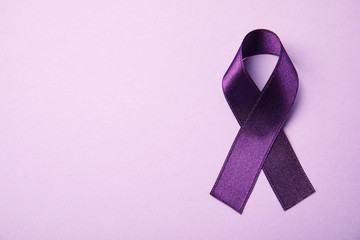 Purple ribbon on pink background, top view with space for text. Domestic violence awareness