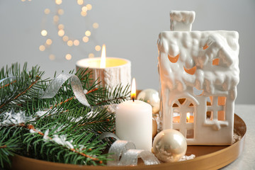 Composition with house shaped candle holder on grey table against blurred background. Christmas decoration
