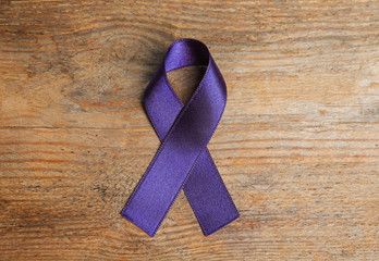 Purple ribbon on wooden background, top view. Domestic violence awareness