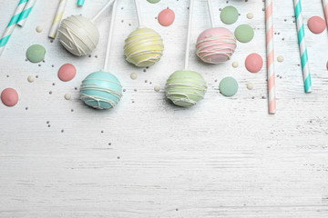 Flat lay composition with sweet cake pops on white wooden background. Space for text