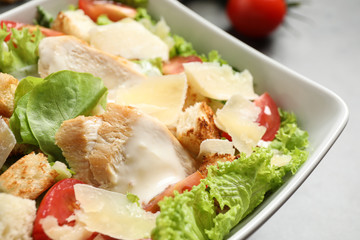 Delicious fresh Caesar salad in bowl on table, closeup
