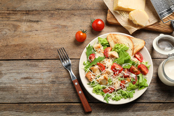 Delicious fresh Caesar salad on wooden table, flat lay