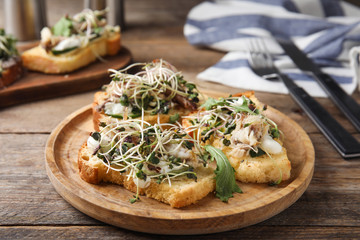 Delicious bruschettas with fish on wooden table