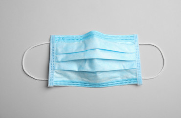 Medical face mask on grey background, top view