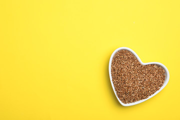 Buckwheat grains on yellow background, top view. Space for text