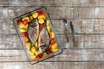 Baked dorado (dorada) fish on a plate, top view