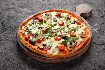 Wooden board with tasty pizza on dark grey background